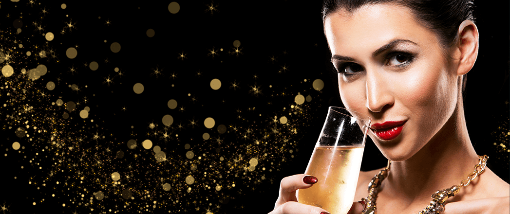 beautiful brunette with dark makeup wearing gold jewellery drinking champagne
